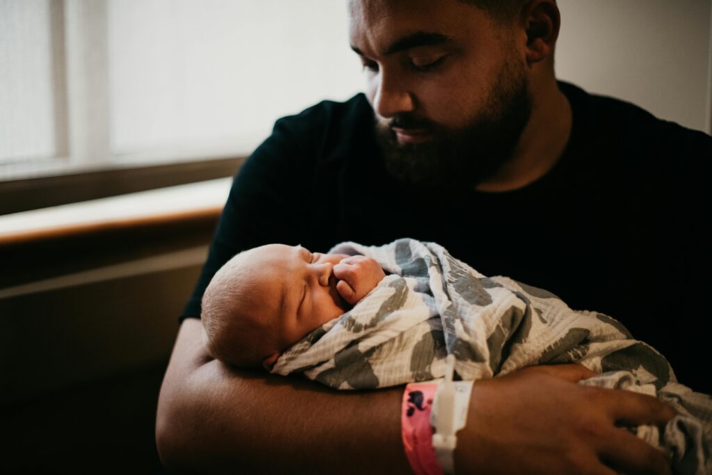 A tender moment of a father holding his newborn baby wrapped in a blanket indoors.