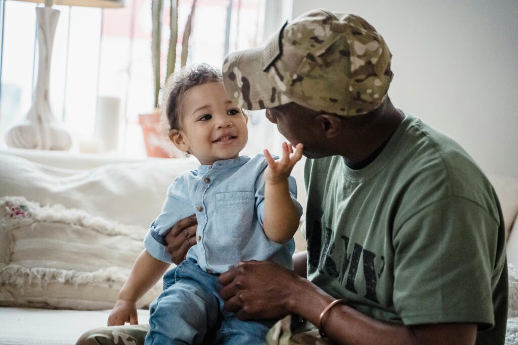 A soldier father shares a joyful moment with his toddler indoors, reflecting family unity.